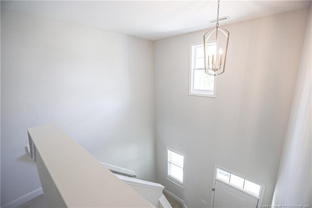staircase with baseboards, visible vents, a chandelier, and a healthy amount of sunlight