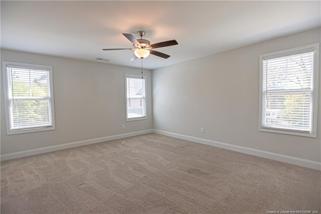 unfurnished room with visible vents, light carpet, baseboards, and ceiling fan