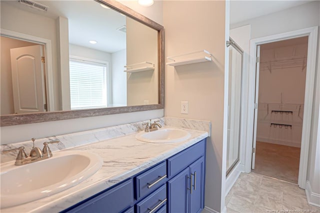 bathroom featuring a stall shower, visible vents, a spacious closet, and a sink