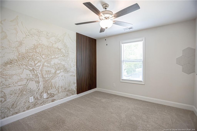 carpeted empty room with baseboards, visible vents, and ceiling fan