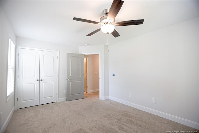 unfurnished bedroom with a ceiling fan, light carpet, baseboards, and a closet