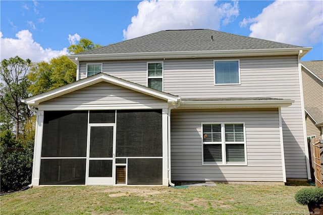 back of house with a lawn, a sunroom, and roof with shingles