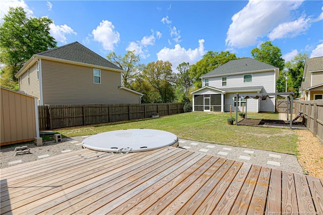 wooden terrace with a sunroom, a fenced backyard, a storage unit, an outdoor structure, and a yard