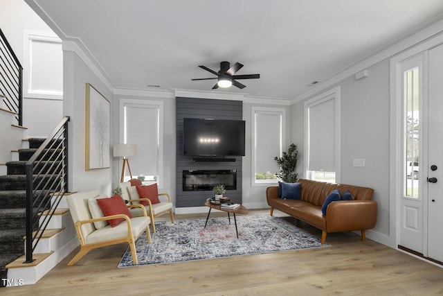 living room featuring stairway, wood finished floors, ornamental molding, and a ceiling fan