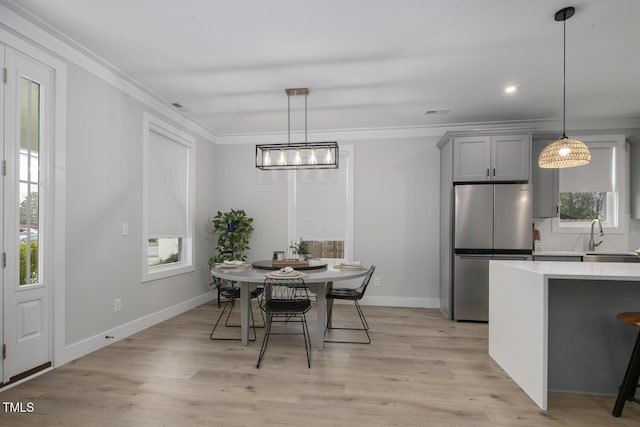 dining space featuring crown molding, light wood-style flooring, and plenty of natural light