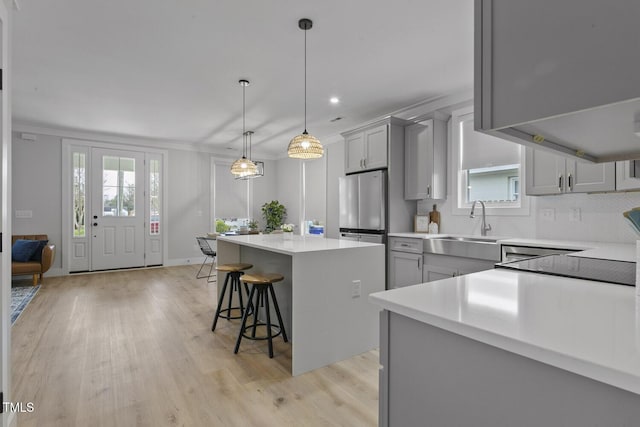 kitchen featuring a center island, a breakfast bar area, light wood-type flooring, light countertops, and gray cabinets