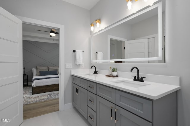 bathroom with double vanity, baseboards, ensuite bathroom, and a sink