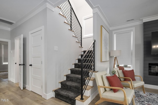 staircase featuring visible vents, baseboards, a large fireplace, and wood finished floors