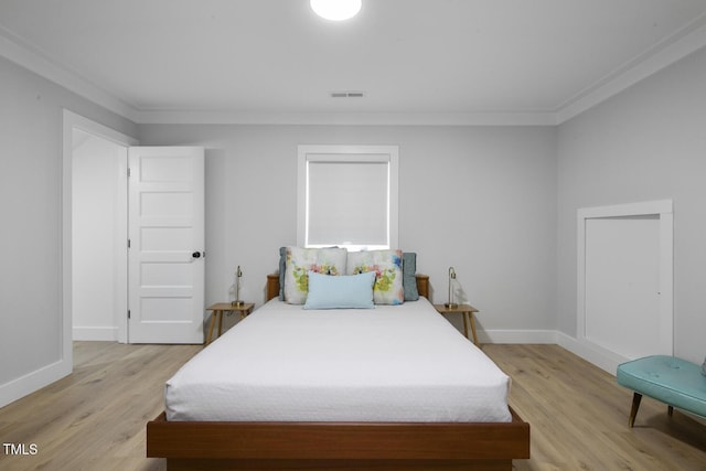 bedroom featuring visible vents, baseboards, ornamental molding, and light wood finished floors