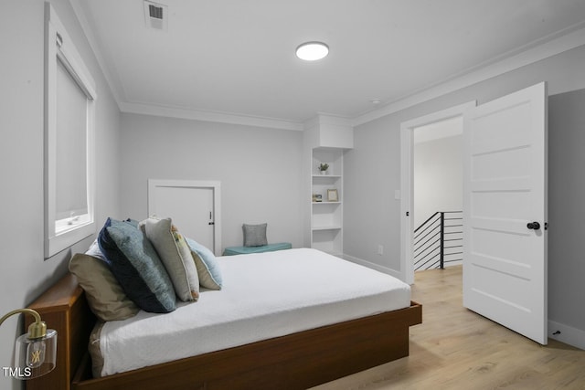 bedroom with visible vents, light wood-style flooring, crown molding, and baseboards