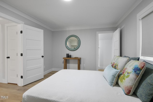 bedroom with light wood finished floors, baseboards, and ornamental molding