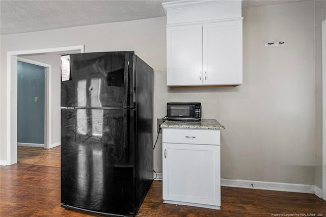 kitchen with baseboards, dark wood-type flooring, black appliances, and white cabinetry