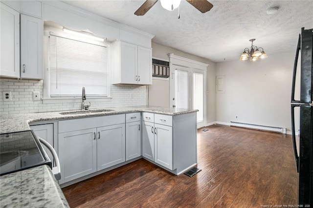 kitchen with a baseboard heating unit, dark wood-type flooring, ceiling fan with notable chandelier, a peninsula, and a sink