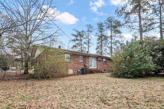 back of property featuring brick siding, central AC, and fence