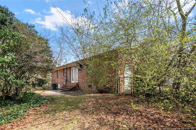 exterior space featuring brick siding, central AC unit, and entry steps