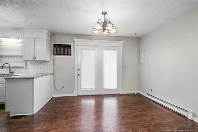 interior space featuring a sink, a textured ceiling, dark wood finished floors, baseboard heating, and an inviting chandelier