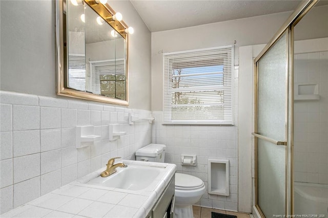 full bathroom with a shower stall, toilet, tile patterned floors, vanity, and wainscoting