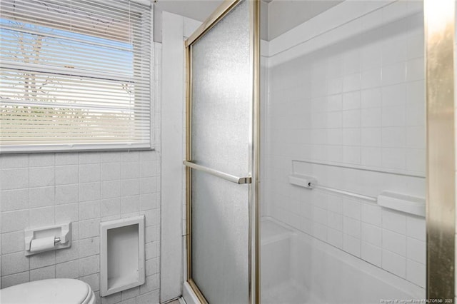 bathroom with a shower with door, toilet, tile walls, and a bathing tub