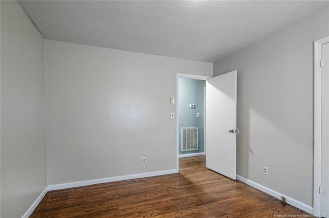 unfurnished bedroom featuring wood finished floors, a textured ceiling, baseboards, and visible vents