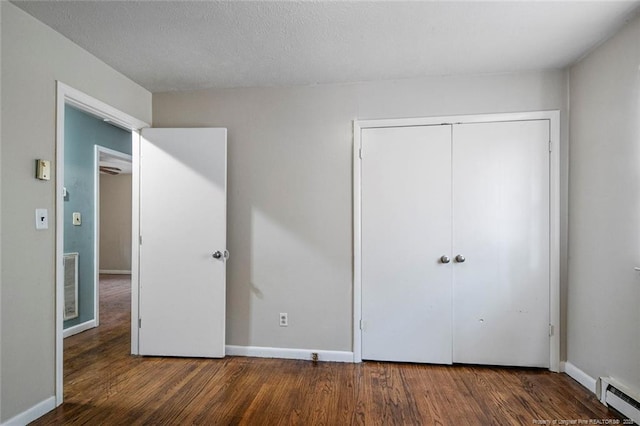 unfurnished bedroom featuring baseboards, visible vents, wood finished floors, and baseboard heating