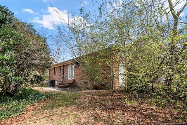 exterior space with brick siding, central AC, and entry steps
