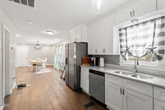 1803 Saint Paul Ave, Fayetteville, NC 28304 - kitchen with a sink, stainless steel appliances, hardwood / wood-style flooring, light countertops, and white cabinetry