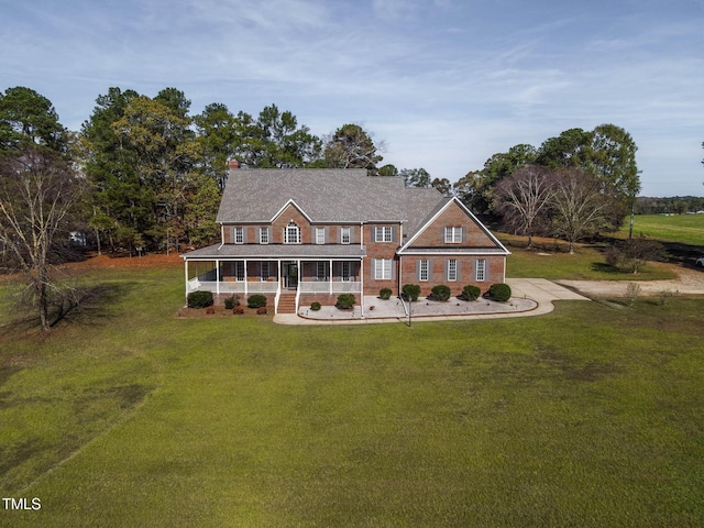 view of front of property with a front yard, a porch, and brick siding