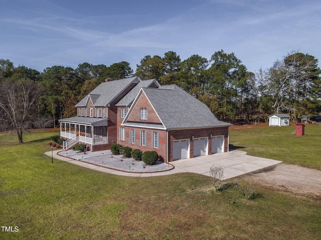 view of front of house featuring brick siding, a front lawn, concrete driveway, covered porch, and a storage unit