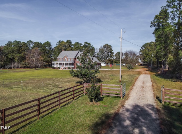 view of road with a rural view, dirt driveway, and a gated entry