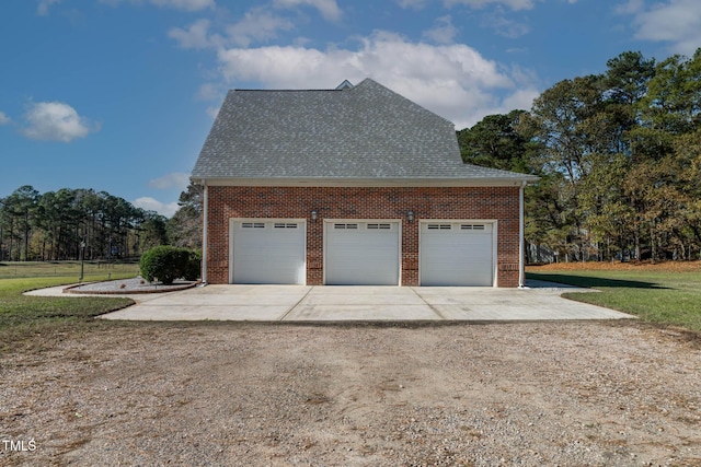 view of side of home with driveway, a yard, a shingled roof, a garage, and brick siding