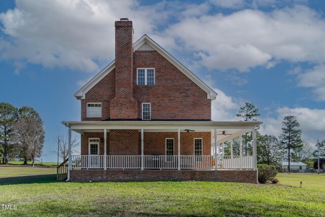 rear view of house with a porch, a yard, brick siding, and ceiling fan