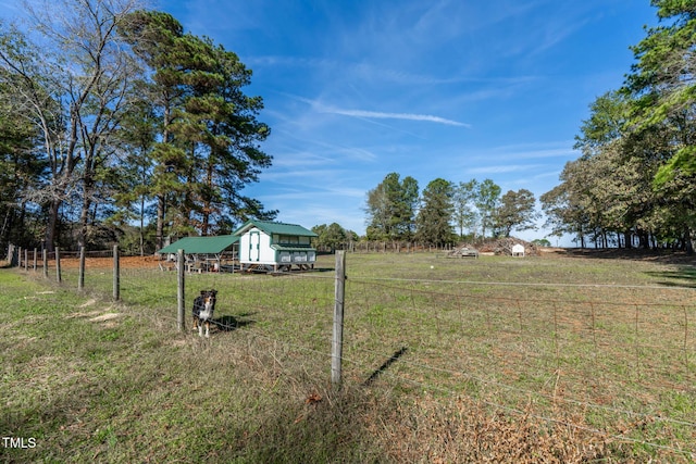 view of yard featuring a rural view, an outdoor structure, and fence