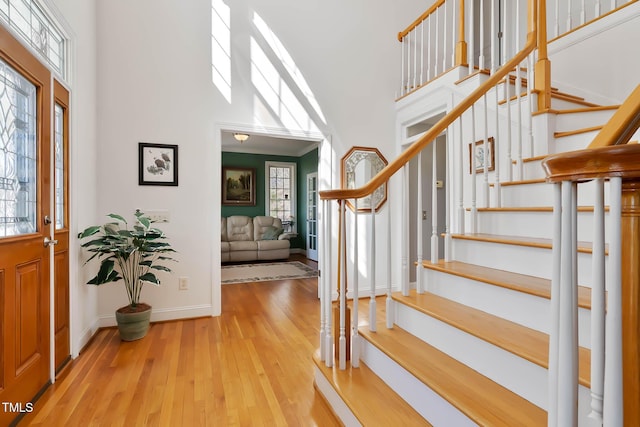 entrance foyer with stairway, wood finished floors, baseboards, and a towering ceiling