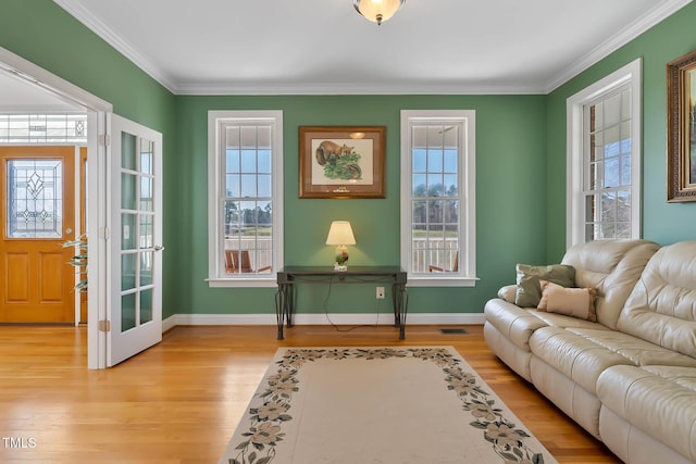 interior space with a wealth of natural light, baseboards, light wood finished floors, and ornamental molding