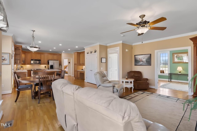 living room with crown molding, a ceiling fan, baseboards, and light wood finished floors