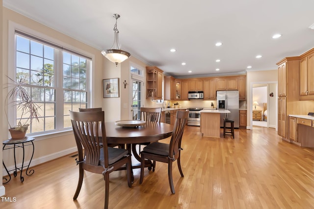 dining area with plenty of natural light, baseboards, crown molding, and light wood-style floors