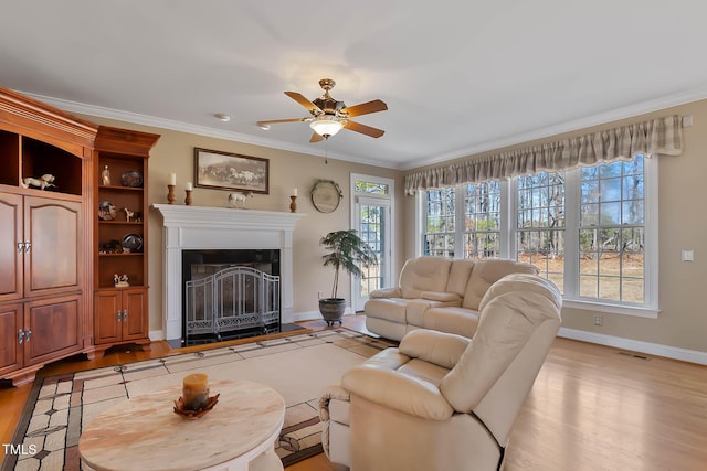 living area featuring a wealth of natural light, crown molding, and ceiling fan