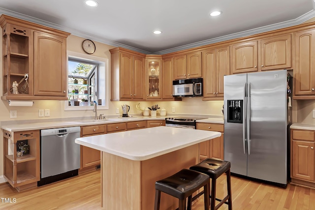 kitchen featuring a breakfast bar area, open shelves, a sink, stainless steel appliances, and light wood-style floors