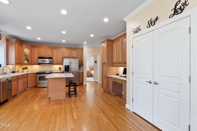 kitchen with a kitchen island, a breakfast bar, ornamental molding, appliances with stainless steel finishes, and a sink