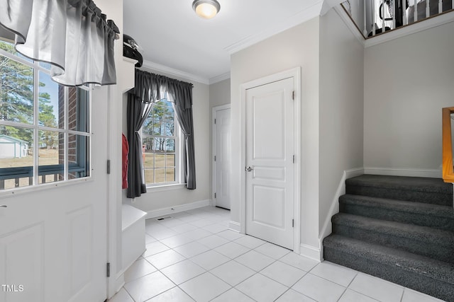 foyer featuring baseboards, light tile patterned flooring, ornamental molding, and stairs