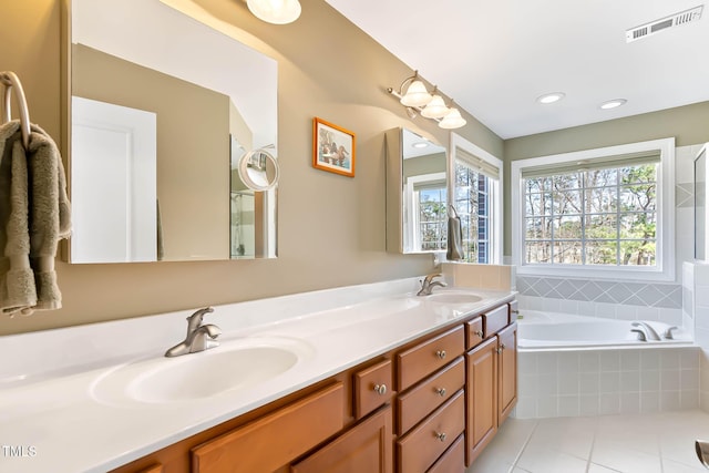 bathroom with visible vents, tile patterned floors, double vanity, a bath, and a sink