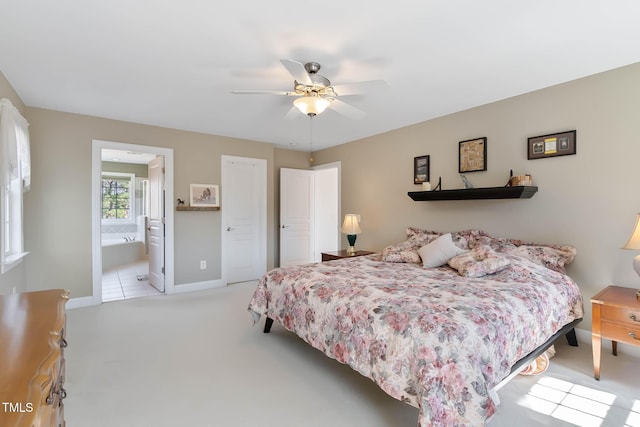 bedroom with light carpet, ceiling fan, ensuite bath, and baseboards