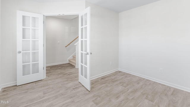 unfurnished room featuring french doors, stairs, baseboards, and wood finished floors