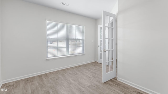 unfurnished room with light wood-type flooring, french doors, baseboards, and visible vents