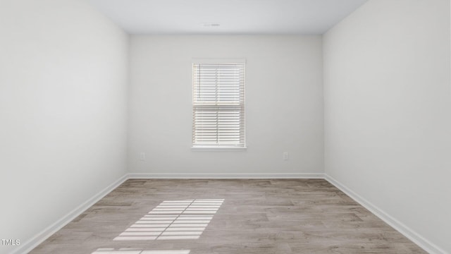 spare room with baseboards and wood finished floors