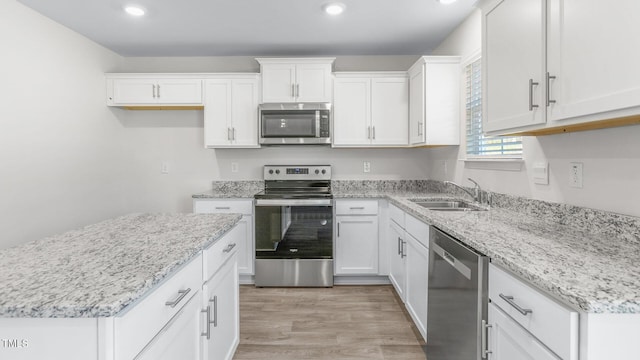 kitchen featuring recessed lighting, light wood-style floors, white cabinets, stainless steel appliances, and a sink