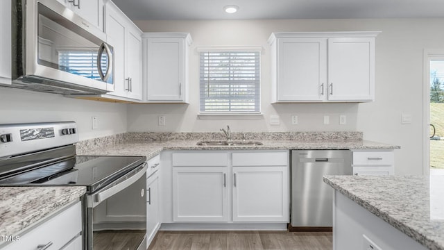 kitchen featuring white cabinetry, light wood-style flooring, appliances with stainless steel finishes, and a sink