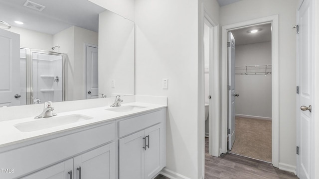 bathroom featuring a sink, visible vents, double vanity, and a shower stall