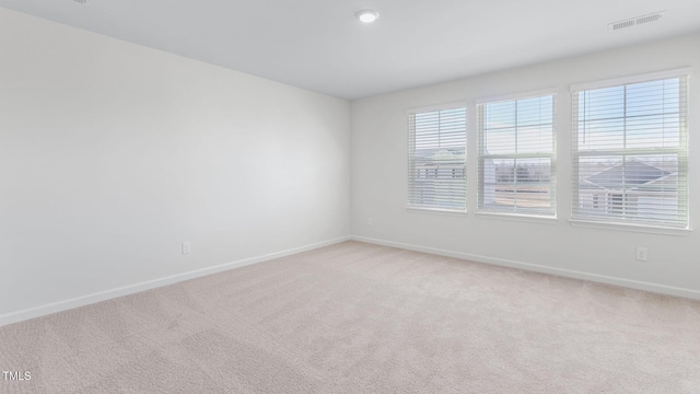 unfurnished room with light carpet, visible vents, and baseboards