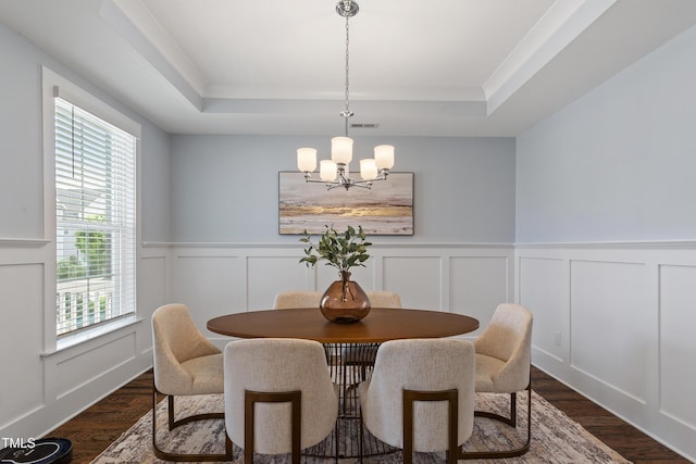 dining room with a notable chandelier, dark wood finished floors, and a raised ceiling